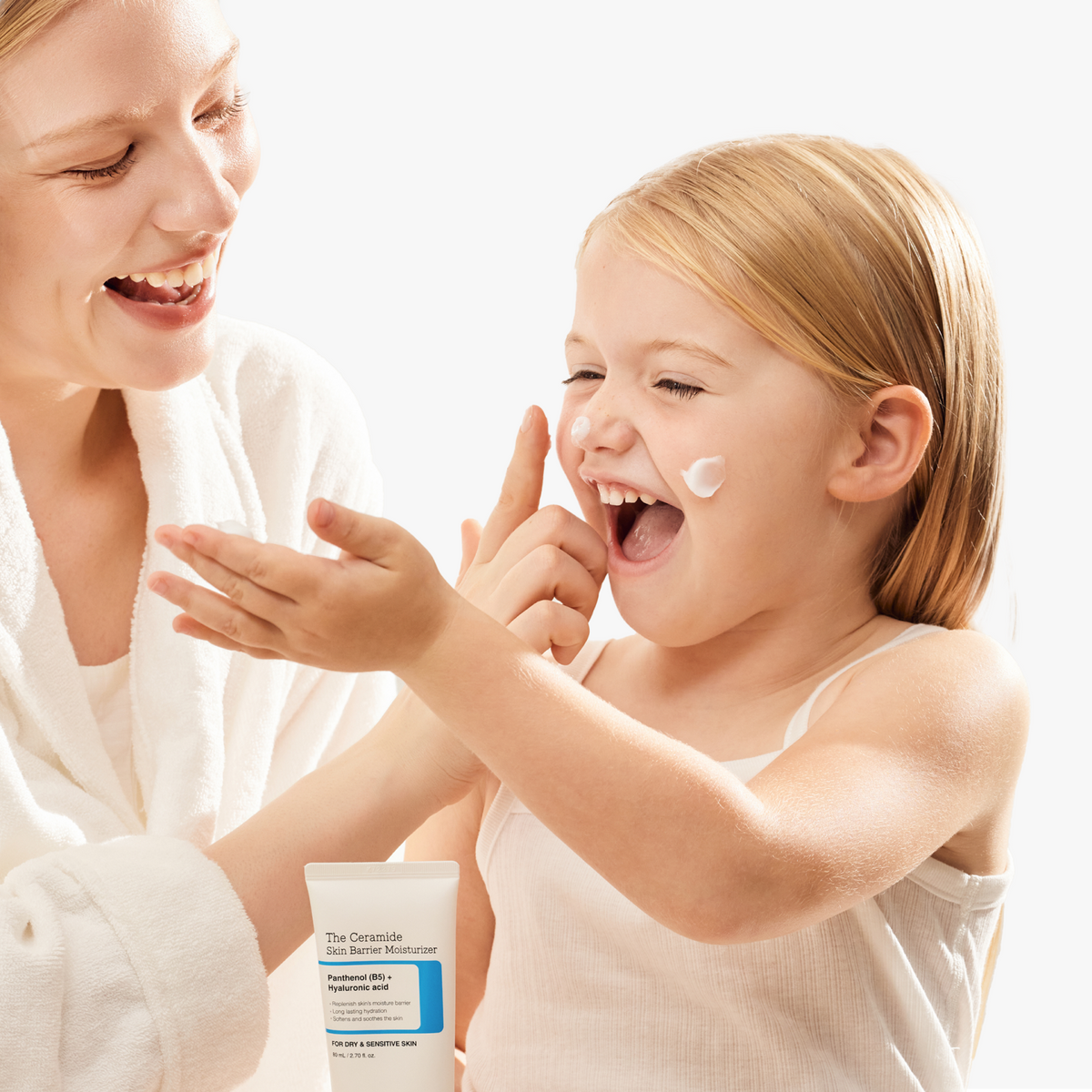 Little girl holding COSRX The Ceramide Skin Barrier Moisturizer and showing applied product on cheek by her mother; dermatologist-tested Korean moisturizer with Ceramides, Cholesterol, Fatty Acids, Panthenol (B5), and 5 types of Hyaluronic Acid that provides deep, lasting hydration and barrier protection. Designed for sensitive and dry skin, absorbs well under foundation without heaviness and is suitable for all ages.