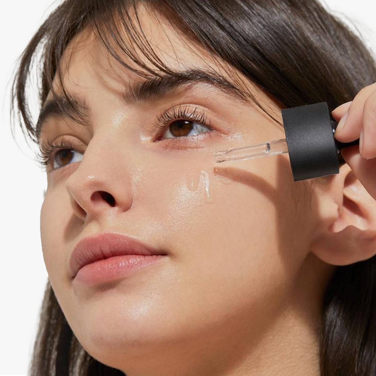 Model applying COSRX The Niacinamide 15 Serum on the cheek with a dropper, showing its gentle texture suitable for sensitive, oily, and acne-prone skin. The formula helps control excess oil, tighten pores, and brighten post-acne marks. Clinical results showed pore count decreased by 45.27% after 4 weeks of consistent use.